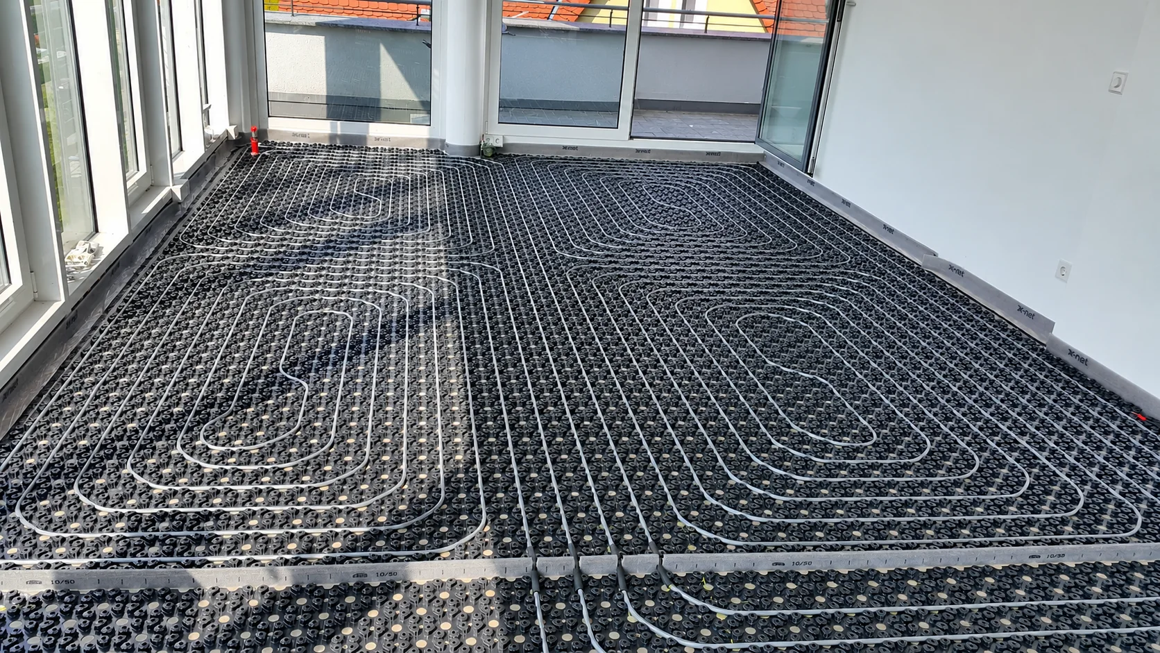 Rozłożona instalacja ogrzewania podłogowego w jasnym pomieszczeniu